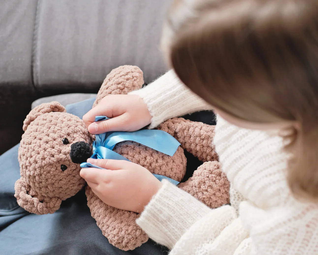 Mp51033728 little girl playing with knitted teddy bear and ties a