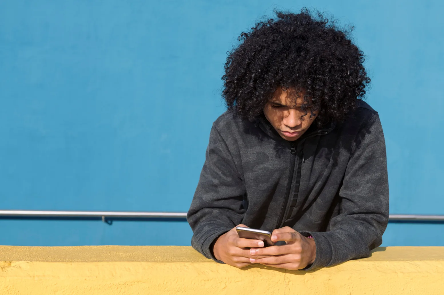 Mp66068987 teenager with curly hair using mobile phone